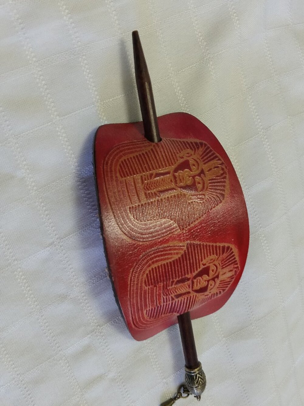 Vintage oval red leather hair clip, carved with a visage motif and wooden pin